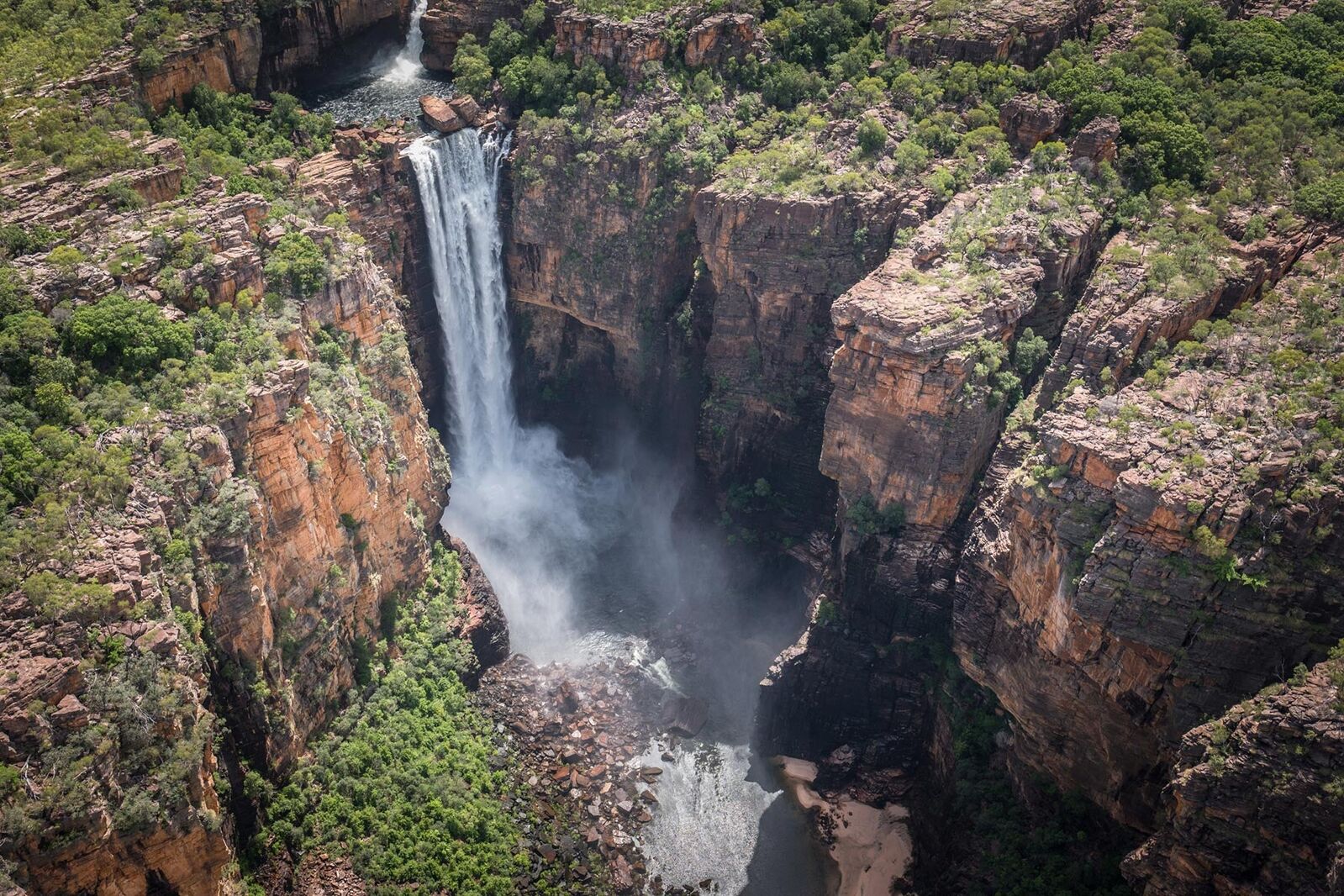 Aerial view of a waterfall plunging into a rocky sandstone gorge