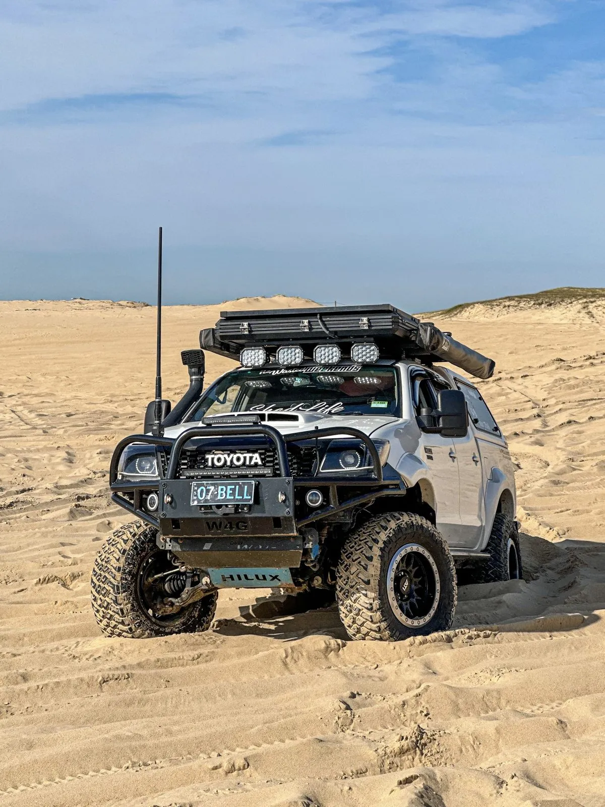 Hilux on a sand dune with four Apex Quad lights under the roof rack